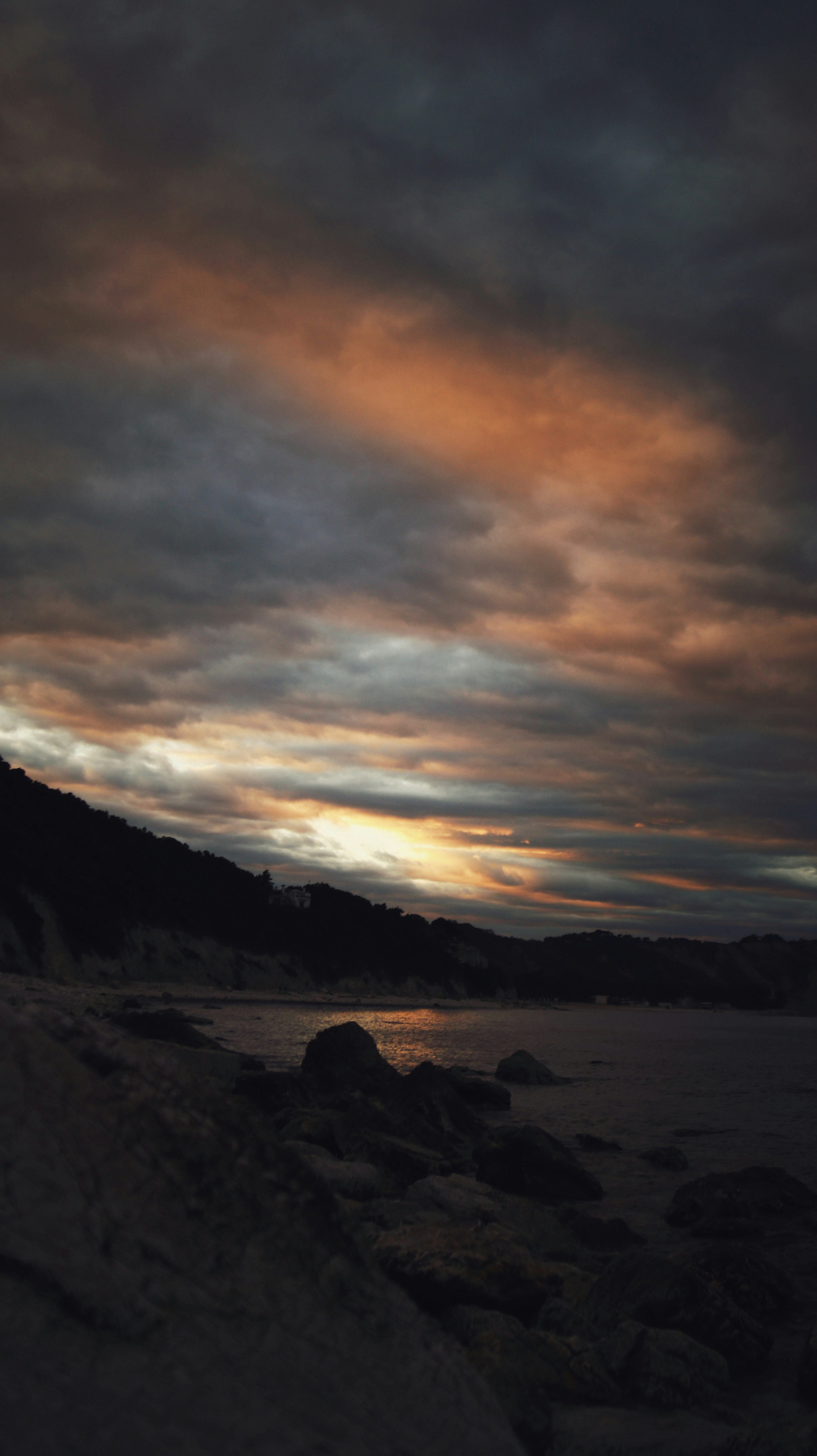 silhouette of mountain near body of water during sunset